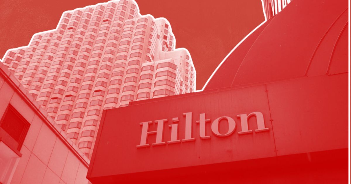 Geometric high-rise with Hilton sign in the foreground, red-tinted image; featured in "San Francisco's Hotel Market in Debt.